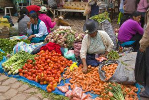 Women sitting on ground with produce at Sunday Market.