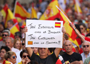 A man holds up a sign which reads "As Spanish as the flag, As Catalan as the Catalan flag" while attending a pro-union demonstration organised by the Catalan Civil Society organisation in Barcelona